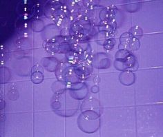 an image of soap bubbles floating in the air on a tile floor with purple background