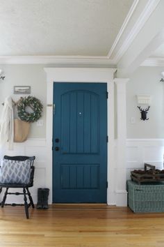 a blue door in a white room with wood flooring and decor on the walls