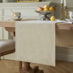 a table with a bowl of fruit on top of it and a white towel hanging from the side