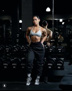 a woman standing in front of a row of dumbs with her hands on her hips