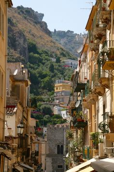 an alley way with many buildings on both sides and a steep hill in the background