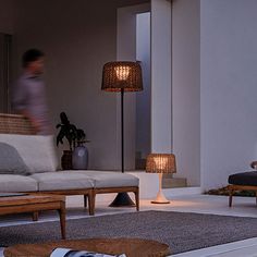 a living room filled with furniture and a woman sitting on a couch in the background