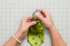 a person holding a green tie with dog paw prints on it and a silver ornament