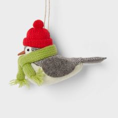 a bird ornament with a red hat and green scarf hanging from it's side