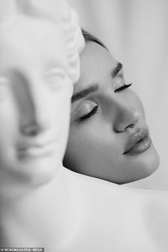 a black and white photo of a woman with her head resting on a mannequin