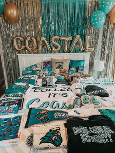 the bed is decorated with miami dolphins shirts and balloons in gold, teal, and white