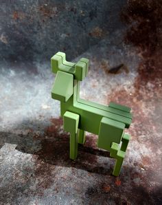 a green toy horse sitting on top of a cement floor next to a rusted surface