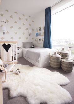 a white bedroom with stars on the wall and rugs in front of two twin beds