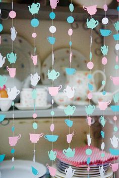 there are many teapots hanging from the ceiling in this kitchen with plates and cups