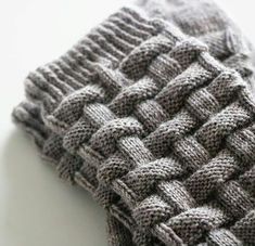 a gray knitted scarf laying on top of a white table