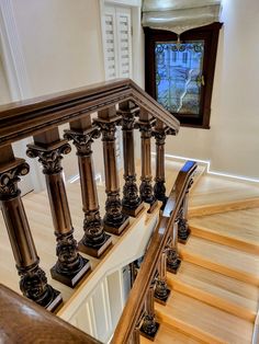 an ornate wooden staircase with railing and handrails in front of a stained glass window