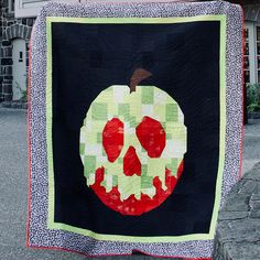 an apple quilt hanging on the side of a building