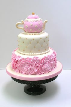 a three tiered cake decorated with pink flowers and a teapot on the top