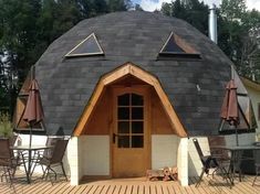 a round building with an open door and wooden decking on the outside, surrounded by umbrellas