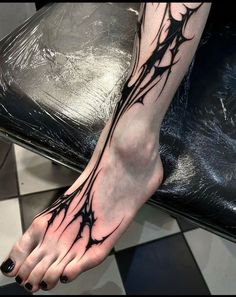 a woman's foot with black ink and vines on the side of her leg