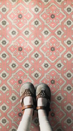 someone's feet wearing sandals and socks standing in front of a patterned wall