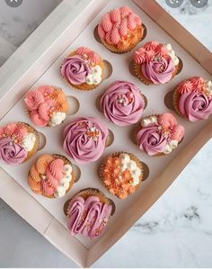 cupcakes with pink frosting in a box on a marble countertop top