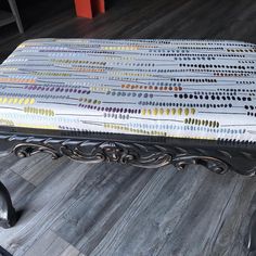 a bench that has been painted with different colors and patterns on it, sitting on a wood floor