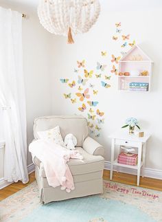 a baby's room with a white chair and butterfly wall decals on the walls