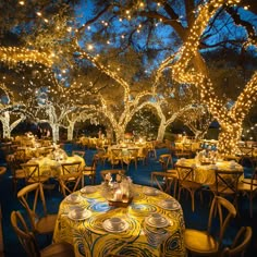 an outdoor dining area with tables and chairs covered in yellow tablecloths, lit by fairy lights