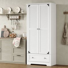 a large white cabinet in a kitchen next to a wall with plates and utensils on it