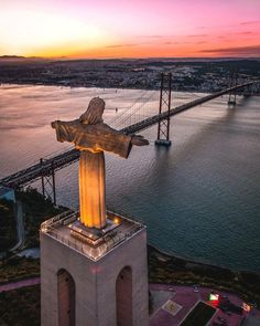 an aerial view of the statue of christ on top of a building with a bridge in the background