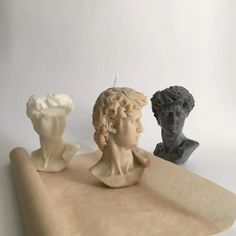 three statues of people sitting on top of a piece of paper