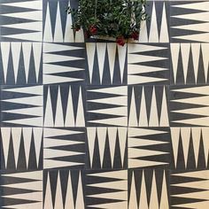 a potted plant sitting on top of a black and white tiled wall