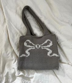 a gray knitted purse sitting on top of a white sheet