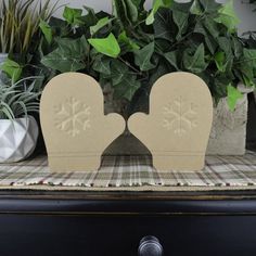 two paper snowflakes sitting on top of a table next to potted plants