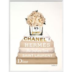 a chanel bottle with flowers on top of it and books stacked in front of it