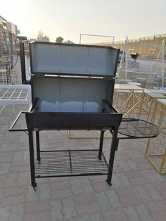 an outdoor bbq grill with two trays on the table and chairs in the background