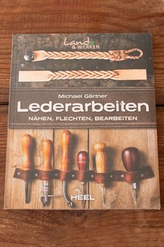 an advertisement for lederarbeiten is displayed on a wooden table with knives