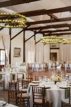 the tables are set with white linens and greenery for an elegant wedding reception