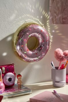 there is a pink object on the desk next to a mirror and other items in front of it