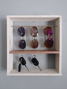 a shelf with sunglasses and keys hanging from it's sides, on which is a key holder