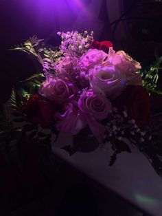 a bouquet of flowers sitting on top of a white vase filled with purple and red flowers