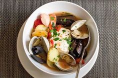 a white bowl filled with seafood and clams on top of a cloth covered table