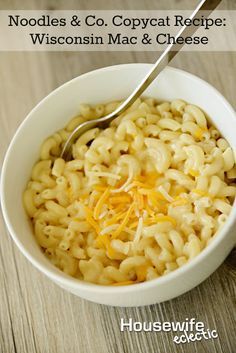 a white bowl filled with macaroni and cheese on top of a wooden table