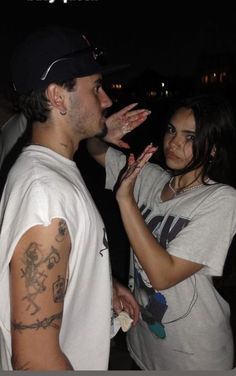 a man and woman standing next to each other with their hands in front of them