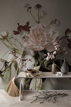 a table topped with vases filled with flowers next to a wallpapered wall