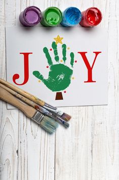 a card with the word joy painted on it next to paintbrushes and watercolors