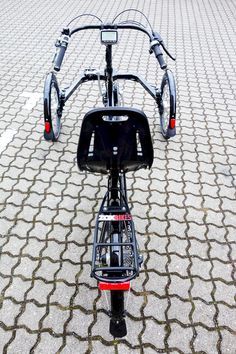 the front end of a bicycle parked on a cobblestone street with no one around it