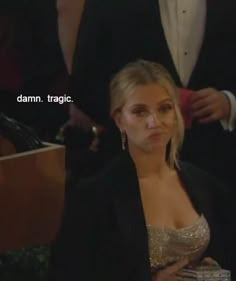 a woman in a black suit and gold dress sitting next to a man wearing a tuxedo