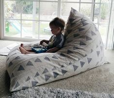 a young child sitting on a bean bag chair in front of a sliding glass door