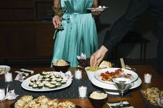 a man and woman are serving themselves food at a table with other dishes on it