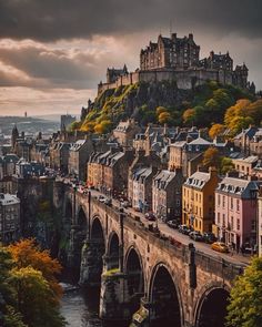 an old bridge crosses over a river in front of a castle on top of a hill