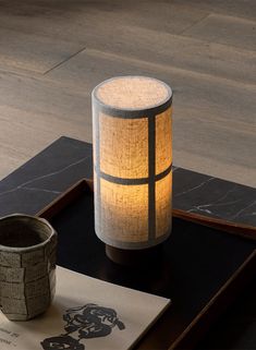 a table topped with a vase next to a lit candle on top of a wooden tray