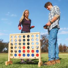 a man and woman standing next to a giant connect game