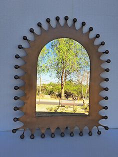 a mirror that is on the wall with some balls around it and trees in the background